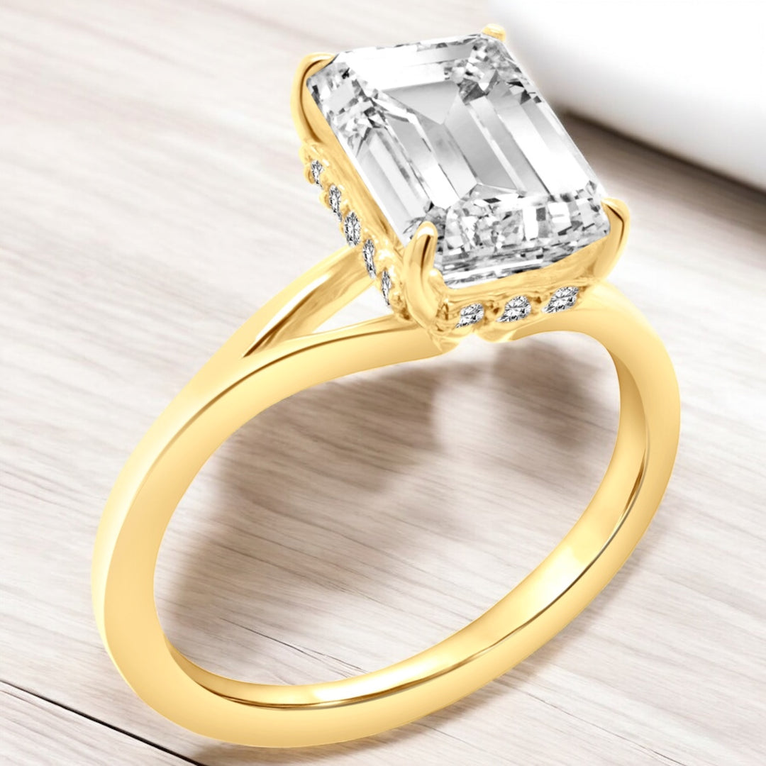 An image showing an angled view of the finished product of the 14 Karat Emerald Shape Hidden Halo Lab Grown Diamond Engagement Ring