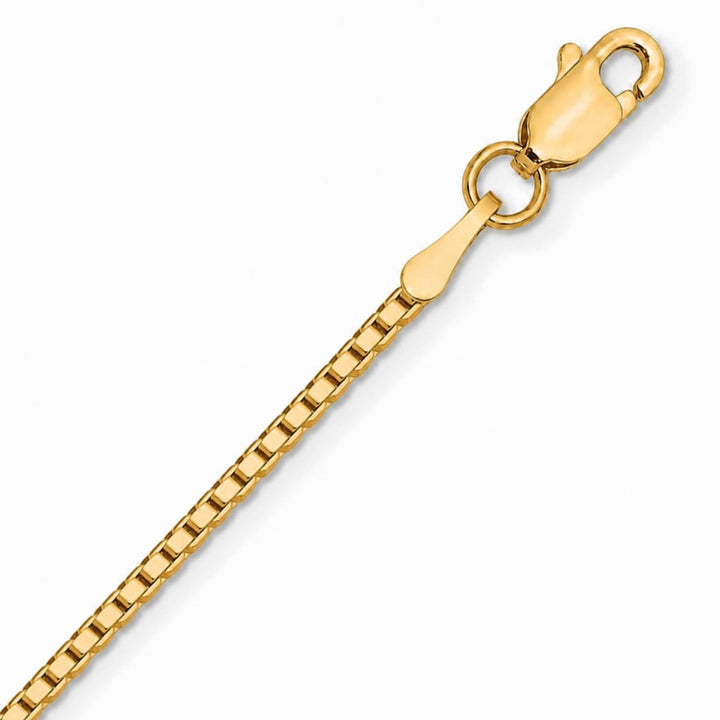 A close up image of a yellow gold box chain on a pure white background
