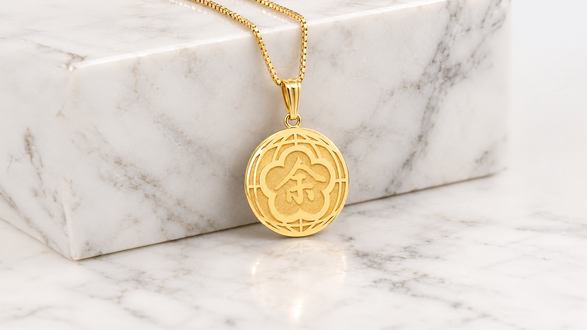 14 karat yellow gold round name pendant on a box chain against white marble, laser engraved and cut from the client's own artwork at AJ's Jewelry in Queens NY