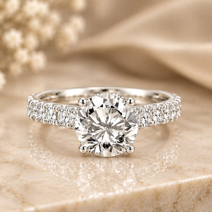 14 karat white gold 3ct round lab grown diamond hidden halo engagement ring with diamond accent band shown from the front on a styled display at AJ's Jewelry in Ridgewood, Queens NY