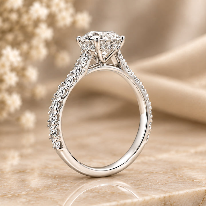 14 karat white gold 3ct round lab grown diamond hidden halo engagement ring with diamond accent band shown from the side on a styled display at AJ's Jewelry in Ridgewood, Queens NY
