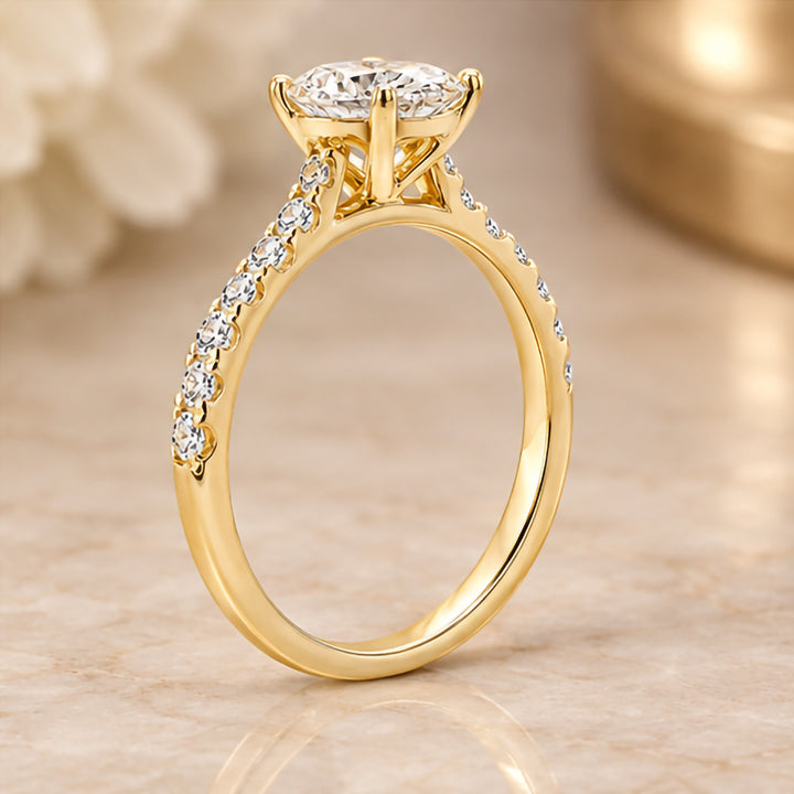 14 karat yellow gold 2ct oval lab grown diamond cathedral engagement ring with diamond accent band shown from the side on a styled display at AJ's Jewelry in Ridgewood, Queens NY