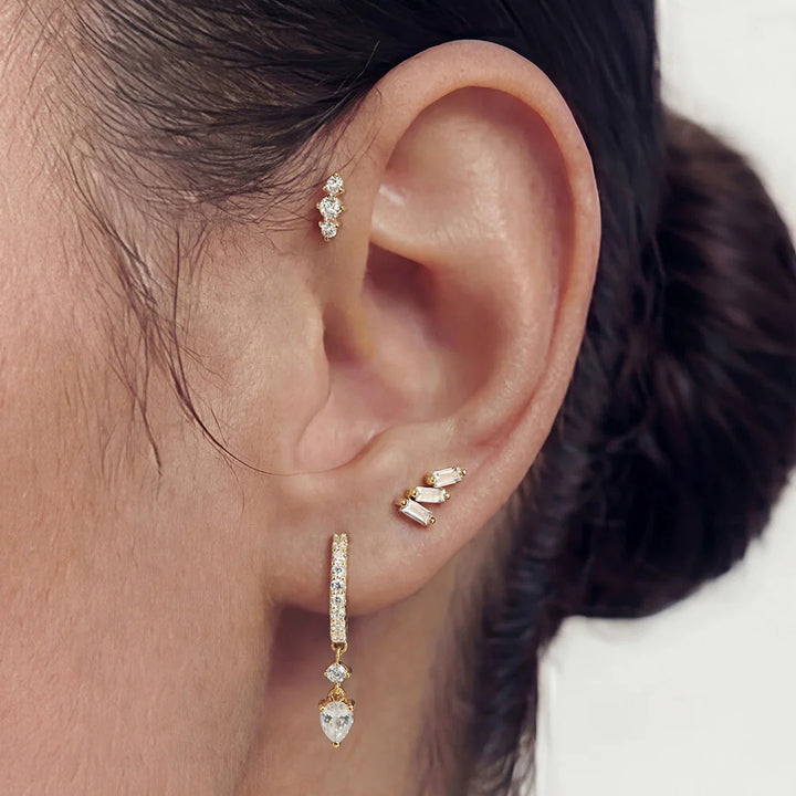 The 14K yellow gold baguette lab grown diamond three-stone stud earrings shown on a model in profile | AJ's Jewelry