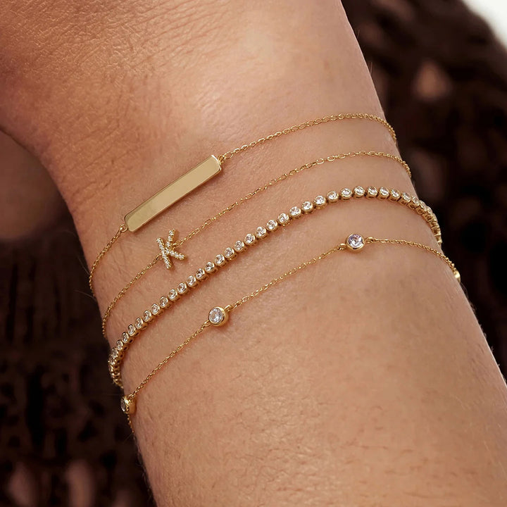 Model wearing the 14K yellow gold bezel-set lab grown diamond station bracelet with layered fine jewelry | AJ's Jewelry