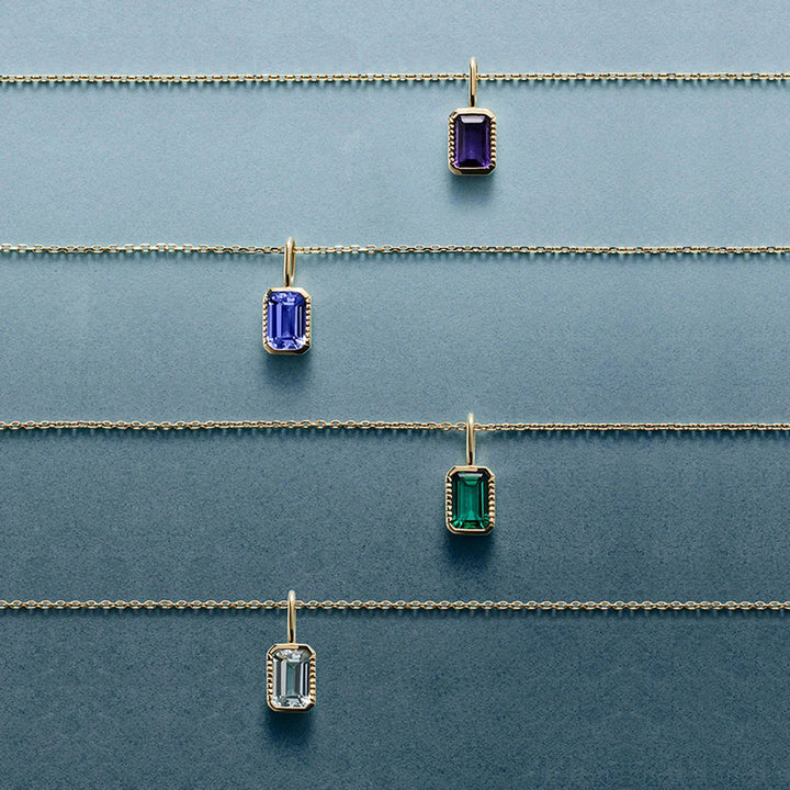 Four 14K yellow gold emerald-cut gemstone pendant necklaces laid flat, including the natural amethyst style | AJ's Jewelry