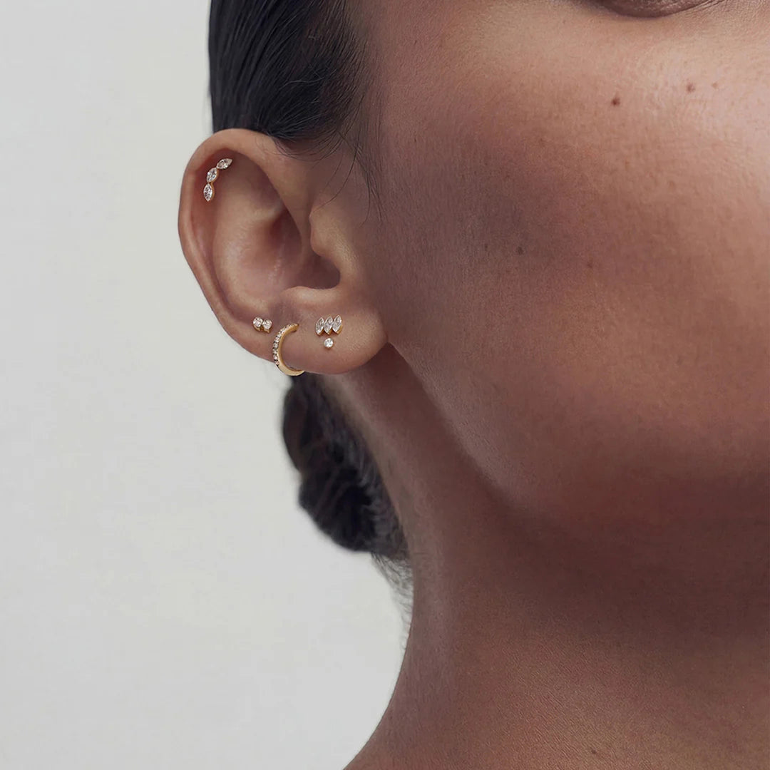 Model wearing the 14K yellow gold marquise lab grown diamond three-stone flat back stud earrings in a styled ear stack | AJ's Jewelry