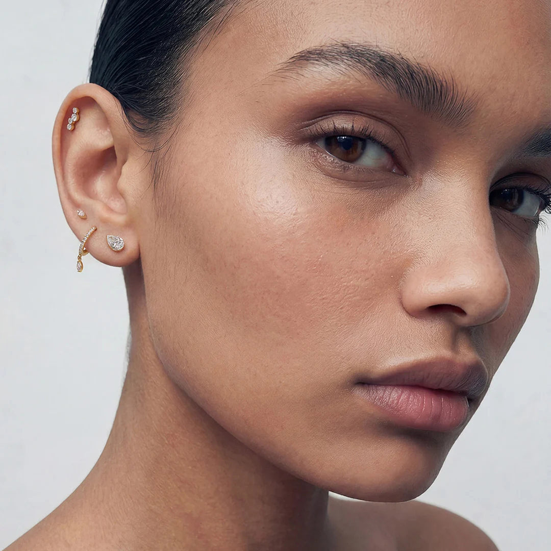 Model wearing the 14K yellow gold pear lab grown diamond flat back stud earrings in a styled ear stack | AJ's Jewelry