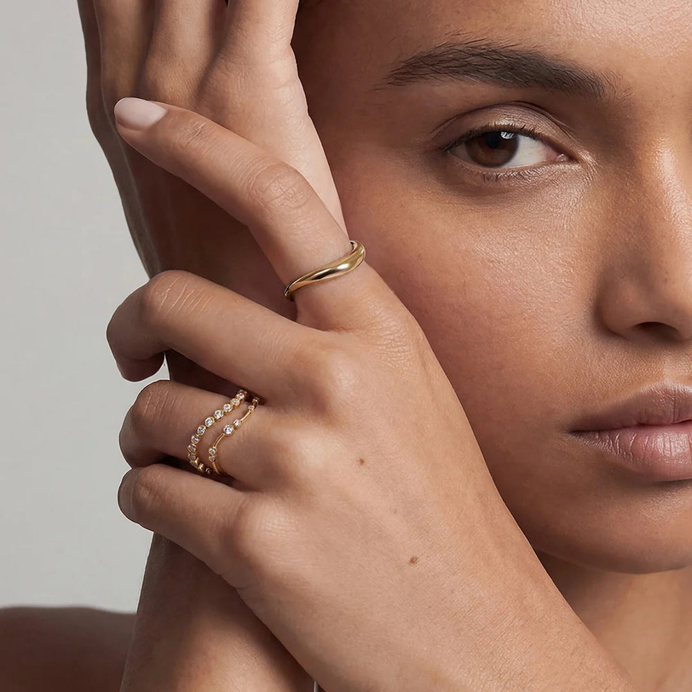 Model wearing the 14K yellow gold polished curved wave band ring in a ring stack | AJ's Jewelry