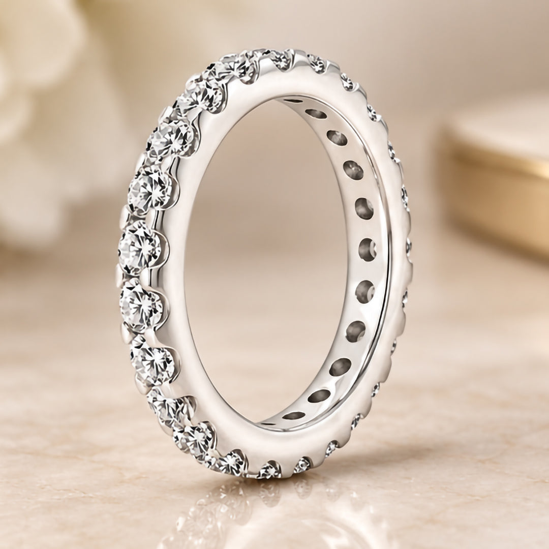 Styled upright photograph of the 14 karat white gold natural diamond eternity band standing on marble at AJ's Jewelry