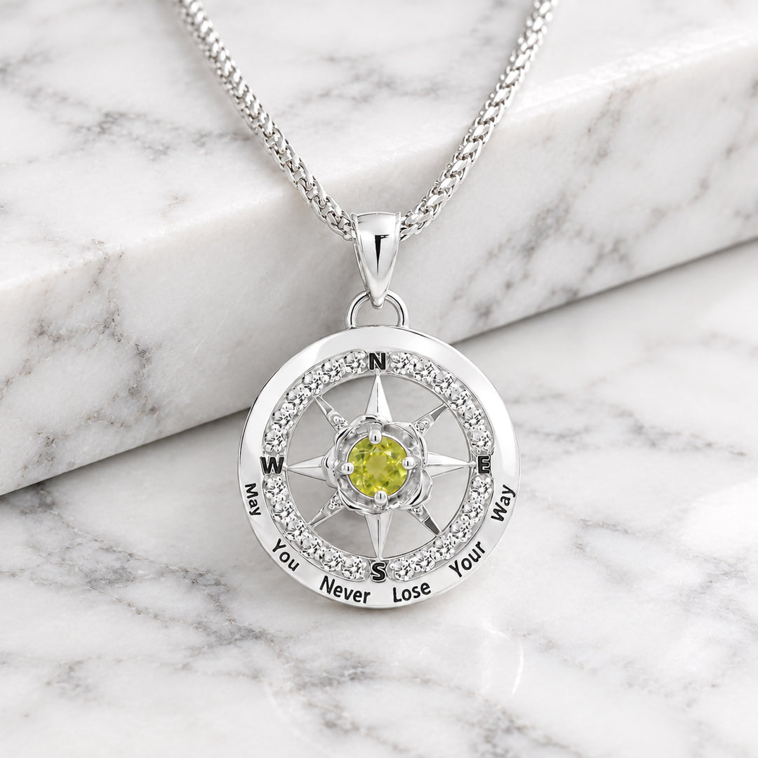 Front view of the 14 karat white gold compass rose pendant showing the ring of natural diamonds and the peridot birthstone at the center