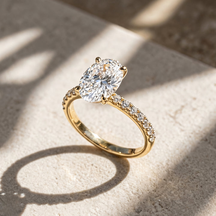2 carat oval lab grown diamond pave engagement ring at an angle on a styled display at AJ's Jewelry Queens NY