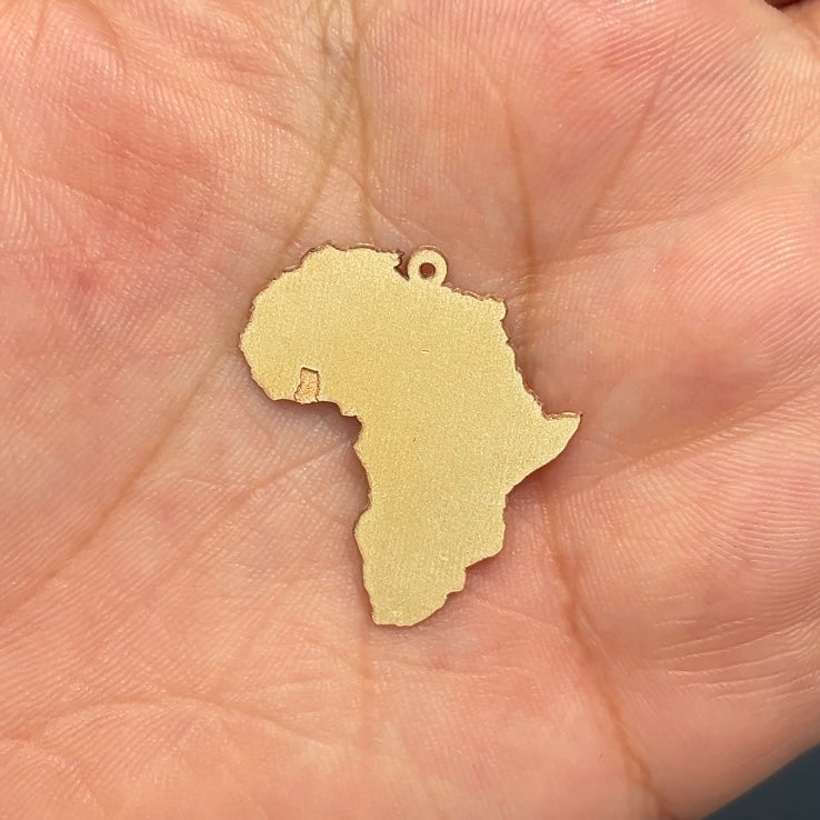 A image of the Africa Continent pendant, just cut out from a sheet of 14 Karat Yellow Gold using a Laser Cutting Machine