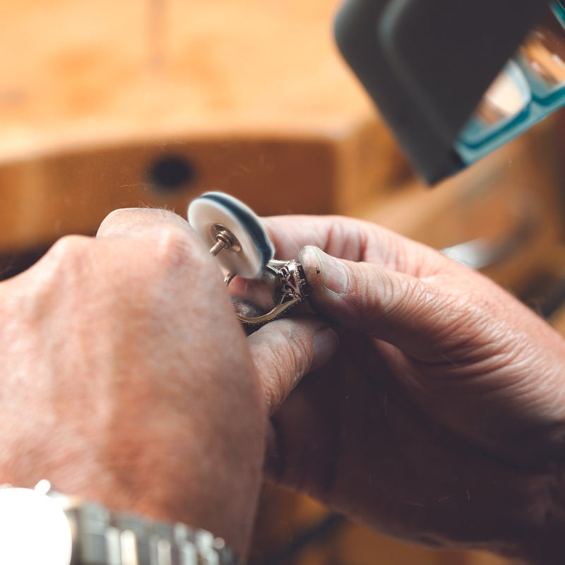 A bench jeweler polishing a ring