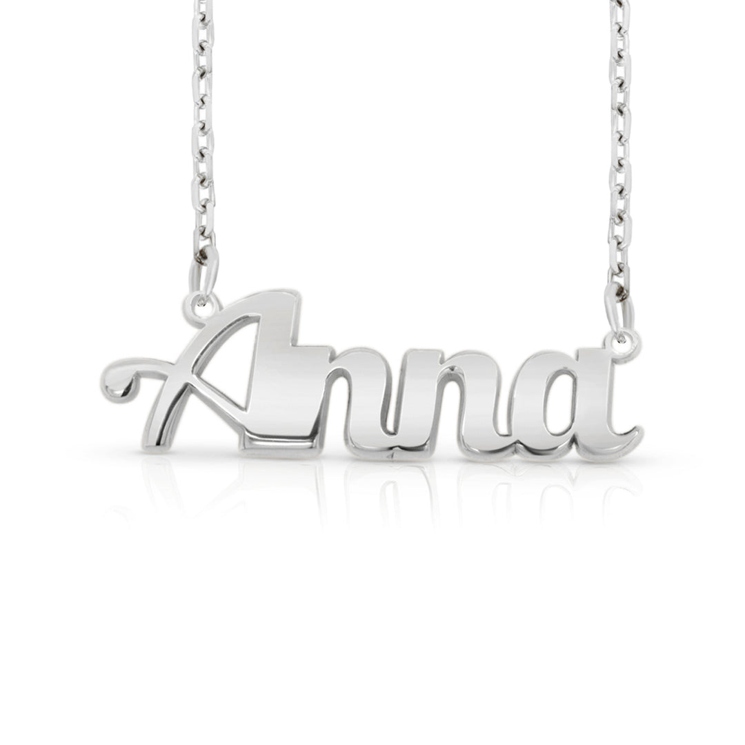 A silver nameplate necklace spelling 'Anna' in a bold font, suspended from a delicate silver chain against a white background.  This photo can change appearance depending on the name input using the custom name builder