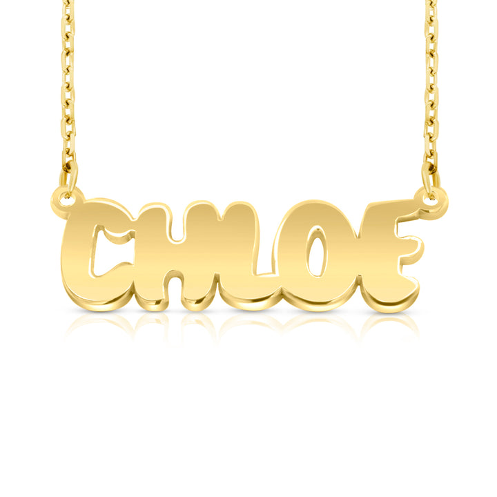 A gold nameplate necklace spelling 'CHLOE' in a bold, rounded font, suspended from a delicate gold chain against a clean white background with a soft reflection below.  This photo can change appearance depending on the name input using the custom name builder