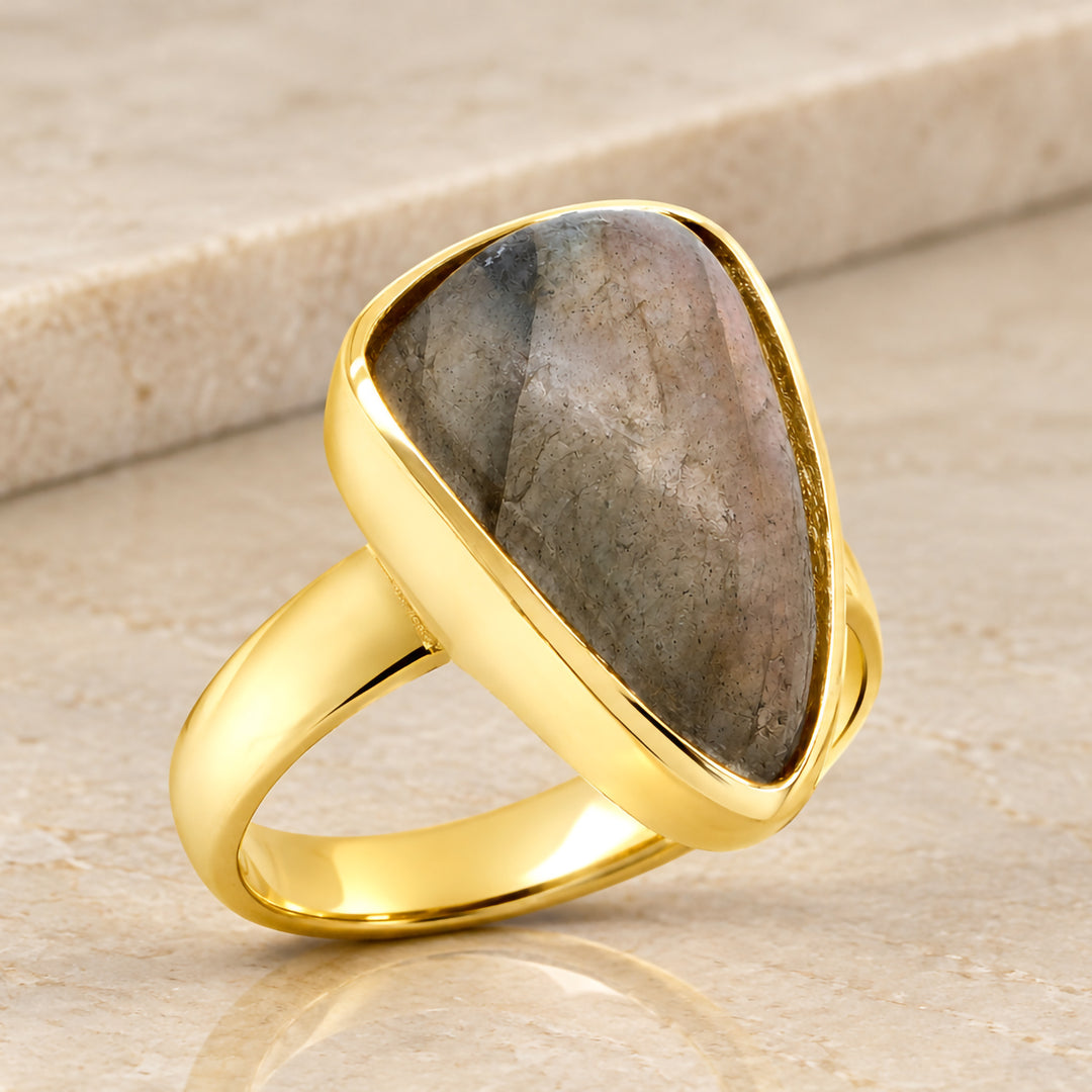 Angled view of the custom 14 karat yellow gold ring showing the mounting wall following the outline of the pear shaped labradorite