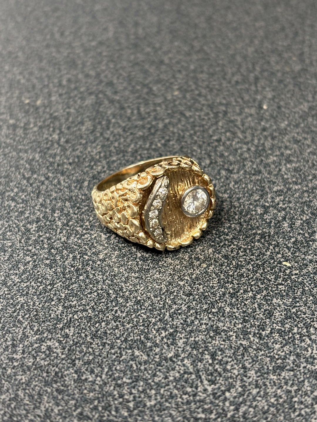 Gold ring with diamond on a gray textured surface