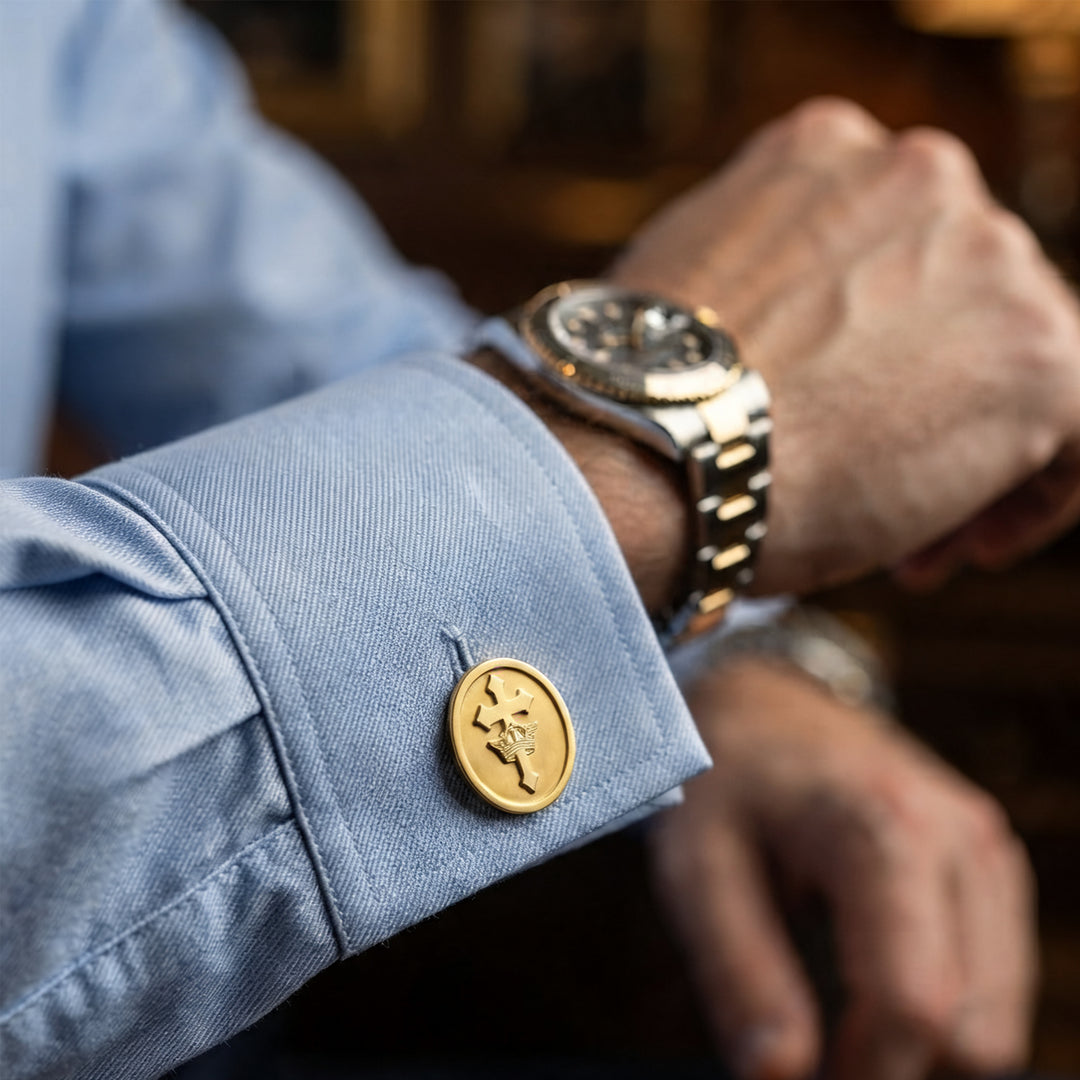 Gold plated St. Helen's Catholic Academy logo cufflink worn on a blue shirt cuff as a retirement gift