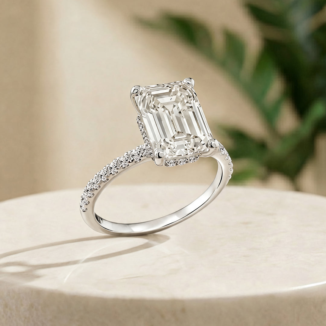 Custom 14KT white gold hidden halo emerald-shape lab-grown diamond engagement ring shown at an angle on a styled display at AJ's Jewelry in Ridgewood, Queens NY