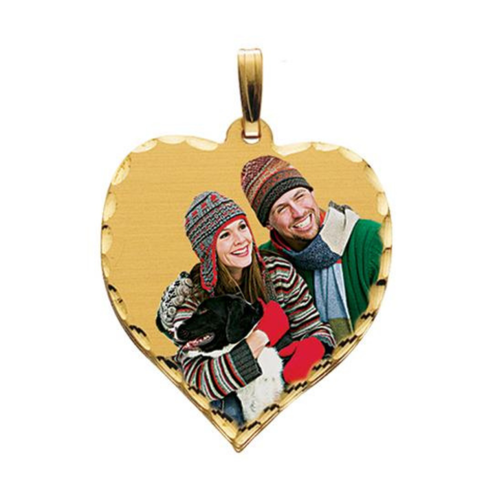 A heart-shaped gold pendant charm featuring a custom photo of a couple in winter clothing, complete with a gold-tone bail at the top, shown against a plain white background.
