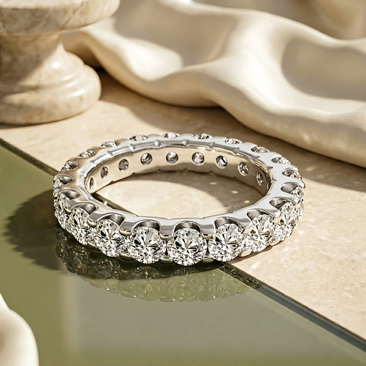 Platinum 3ct lab grown diamond eternity band shown from the front on a styled display at AJ's Jewelry in Ridgewood, Queens NY
