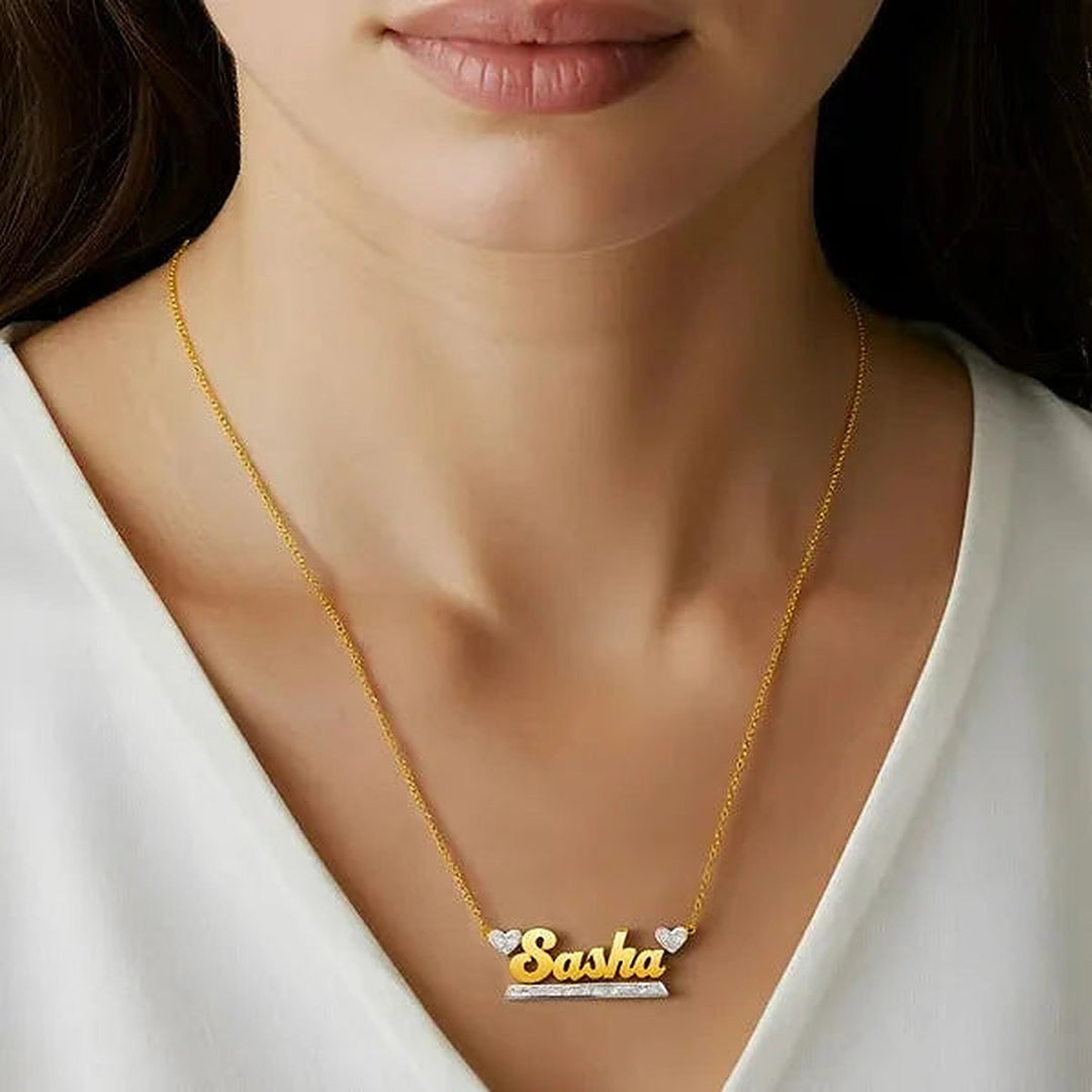 Model wearing the 14 Karat Bold Name Necklace with Two Hearts in 14K yellow gold personalized with the name Sasha | AJ's Jewelry