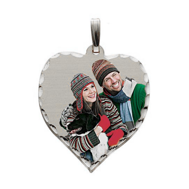 A heart-shaped silver pendant charm featuring a custom photo of a couple in winter clothing, complete with a silver bail at the top, shown against a plain white background.