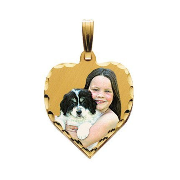 A heart-shaped gold picture pendant featuring a custom photo of a girl hugging a black and white puppy, shown on a plain white background.